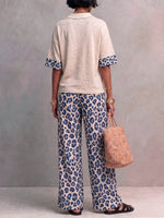 Women's Two-piece Set Featuring A Casual Loose-fitting Short-sleeved Collared Pullover Top And High-waisted Loose-fitting Wide-leg Trousers With A Leopard Print.